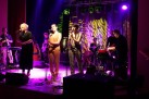 Na scenie instrumentaliści i wokalistki podczas występu. 