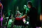 Instrumentaliści podczas występu. Scena oświetlona jest zielonym światłem. 