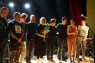 Zdjęcie grupowe muzyków. Jedna z kobiet trzyma w dłoniach kwiaty. 
