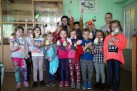 Zdjęcie grupowe uczestników ,,warsztatów z jajem' wraz prowadzącą. Dzieci trzymają w dłoniach ozdobione jaja wielkanocne. 