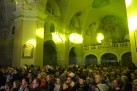 Zdjęcie przedstawia publiczność zgromadzoną w kościele. Mury świątyni oświetlone są zielonym światłem emitowanym przez lampy. 