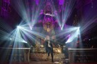 Na zdjęciu wokalistka i gitarzysta podczas swojego występu. Lampy sceniczne emitują dużo białego światła. 