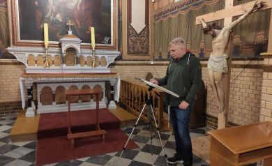 Mężczyzna malujący obraz w świątyni. Widać wnętrze kościoła: ołtarz, krzyż, ławy, zdobne wykończenia ścian, podłogę przypominającą szachownicę, dywan.