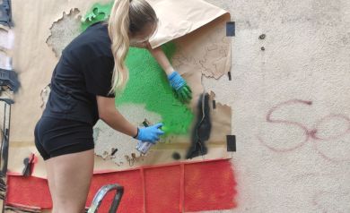 Kobieta malująca mural na drabinie 