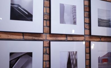 Na ścianie wiszą fotografie, na których dominują odcienie bieli i czarnego.