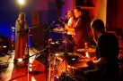 Zdjęcie przedstawia muzyków grających na instrumentach oraz wokalistkę. 