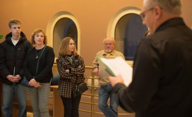 Uczestnicy wystawy oraz prowadzący z teczką w lewej ręce.