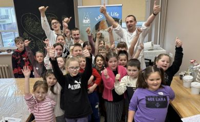 Grupa dzieci i Panowie z warsztatów laboratoryjnych uśmiechnięci pokazują kciuki w górę