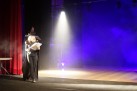 Uczestniczka projektu na scenie w stroju czarownicy. W tle niebiesko-białe światło i dym.