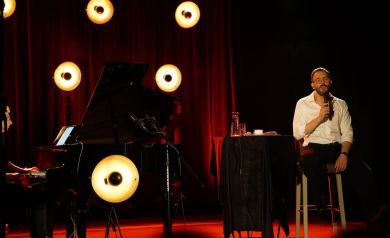 Dwóch muzyków na scenie w blasku lamp oświetlających scenę. 