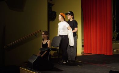 Na scenie trzech młodych artystów podczas sceny teatralnej.