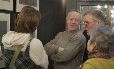 Uczestnicy wernisażu rozmawiający z twórcą wystawianych dzieł.