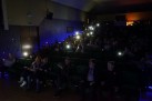 Na zdjęciu publiczność. Kilkoro osób ma zaświecone latarki w telefonie. 