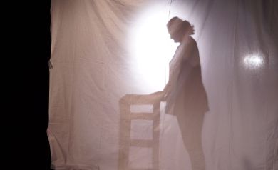 Zdjęcie przedstawia teatr cieni, na którym widoczna jest sylwetka jednej osoby oraz mebel, prawdopodobnie stół.