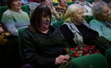 Na zdjęciu publika zebrana na Jubileuszu 80-lecia Miejskiej i Gminnej Biblioteki Publicznej w Strzelcach Opolskich. Jedna z kobiet trzyma na kolanach róże.