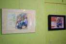 Zdjęcie prezentuje obraz i plakat z identyczną grafiką, która przedstawia mężczyznę opartego o ścianę i psa. Dzieła znajdują się jeden w białej ramie, drugi zaś w czarnej.