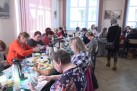 Uczestnicy konkursu zdobienia jaj wielkanocnych przy wspólnych stołach. Pracują nad swoimi dziełami.