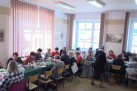 Uczestnicy konkursu zdobienia jaj wielkanocnych siedzą przy stołach i ozdabiają jaja.