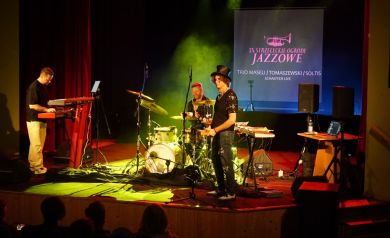 Na scenie trwa występ artystyczny, gdzie artyści prezentują swoje talenty i umiejętności.