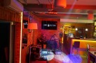 Dwóch mężczyzn grających na gitarach w klimatycznie oświetlonej restauracji. 