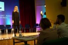 Młoda dziewczyna występująca na scenie. Widać część jury. 