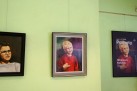 Zdjęcie przedstawia wiszące na zielonej ścianie dwa obrazy w ramkach ukazujące portrety i jedną ramkę z plakatem dotyczącym wydarzenia. 