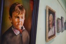 Zdjęcie przedstawia wiszące na ścianie obrazy w ramkach ukazujące portrety. Przybliżenie na jedno z dzieł. 