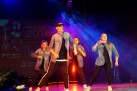 Na scenie grupa taneczna podczas swojego występu. W tle niebiesko-różowe światło i unoszący się ciężki dym.