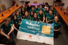 Zdjęcie grupowe uczestników. Na środku plakat z napisem ,,Równać szanse'. Wokół młodzieży stoją stoły oraz krzesła.