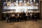 Zdjęcie grupowe uczestników wyjazdu na tle obrazu przedstawiającego scenę z ostatniej wieczerzy.