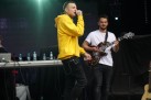 Na zdjęciu mężczyzna w żółtej bluzie śpiewa do mikrofonu. Obok niego gitarzysta w białej koszulce.