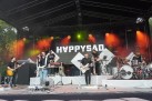 Na zdjęciu zespół muzyczny podczas swojego występu na scenie oświetlanej przez czerwone i żółte światło. 