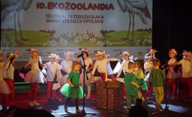 dzieci przebrane za bociany i żabki tańczą na scenie sali widowiskowej