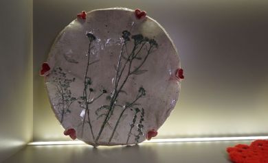 Na zdjęciu dzieło ceramiczne, o nieregularnych kształtach, z motywem roślinnym i czerwonymi serduszkami wokół. W prawym dolnym rogu wiać część czerwonej serwety. - powiększ