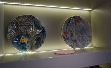 Na zdjęciu dwa elementy ceramiczne w oświetlonej wnęce. Po środku widać również różową serwetę.  - powiększ