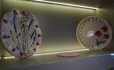 Na zdjęciu dwa elementy ceramiczne w oświetlonej wnęce. Po środku widać również pomarańczową serwetę.  - powiększ