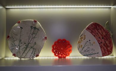Na zdjęciu dwa elementy ceramiczne w oświetlonej wnęce. Po środku widać również pomarańczową serwetę.  - powiększ