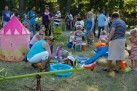 Atrakcja dla dzieci, huśtawki, zjeżdżalnia, klocki. Na zdjęciu widać również osoby dorosłe i dzieci. 