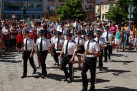 Orkiestra dęta idąca w przemarszu. W tle tłum ludzi. 
