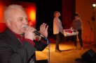 Na zdjęciu mężczyzna mówiący do mikrofonu. W tle dwie kobiety trzymają tort.