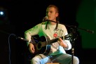 Mężczyzna gra na gitarze i śpiewa do mikrofonu. 