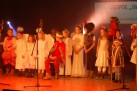Na zdjęciu widać dzieci występujące w przedstawieniu teatralnym, prawdopodobnie w jasełkach, na co wskazują kostiumy i charakter występu. 