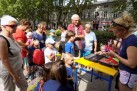 Grupa dzieci i dorosłych. Jedna z kobiet pisze markerem po balonie do modelowania. W tle widać drzewa i zabudowę miejską. 