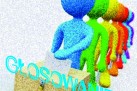 Na obrazku widzimy kolorowe, schematyczne postacie ustawione w kolejce do urny wyborczej. Pierwsza postać (niebieska) wrzuca kartkę do skrzynki. Za nią stoją kolejne sylwetki w innych kolorach. Na dole, po skosie, widnieje duży napis w jasnoniebieskim kolorze: „GŁOSOWANIE!!!”. 