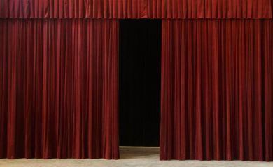To scena teatralna z czerwonymi, częściowo rozchylonymi kurtynami. - powiększ