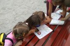 Dzieci analizujące mapy leżące na ławce. Używają również kompasu.