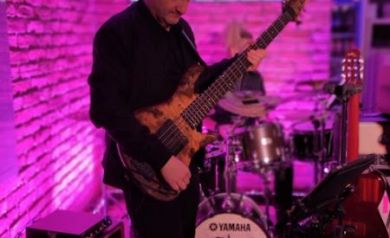 Mężczyzna grający na gitarze w blasku fioletowego światła.