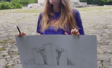 Młoda artystka dumnie pozuje ze swoją pracą, na której narysowany jest Pomnik Czynu Powstańczego na Górze św. Anny.