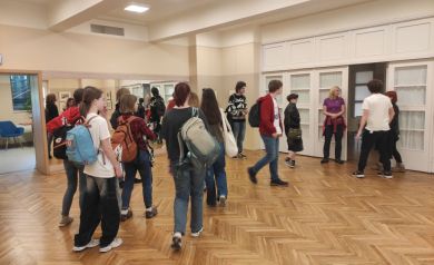 Grupa uczestników w jasnym pomieszczeniu, w którym znajduje się drewniana podłoga w jodełkę 