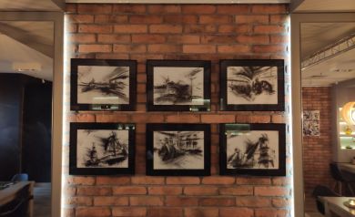 Na ceglanej ścianie sześć obrazów czarno białych wernisażu wystawy ,,Drawing With Coal: UK Industry' Jordana L Rodgersa